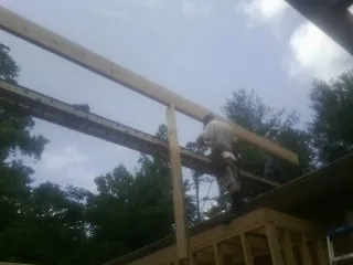 Carpenter setting a ridge beam over a new addition frame — Ice Dam Removal by Roofing Brothers in Poole