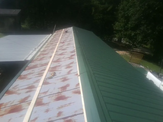 Old rusted panels beside newly installed green metal roofing — Wind Damage Roof Repair by Roofing Brothers in Poole