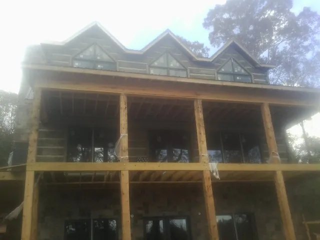 Dormers and porch framing on a large log home under construction — Roof Coating work by our crew in Poole