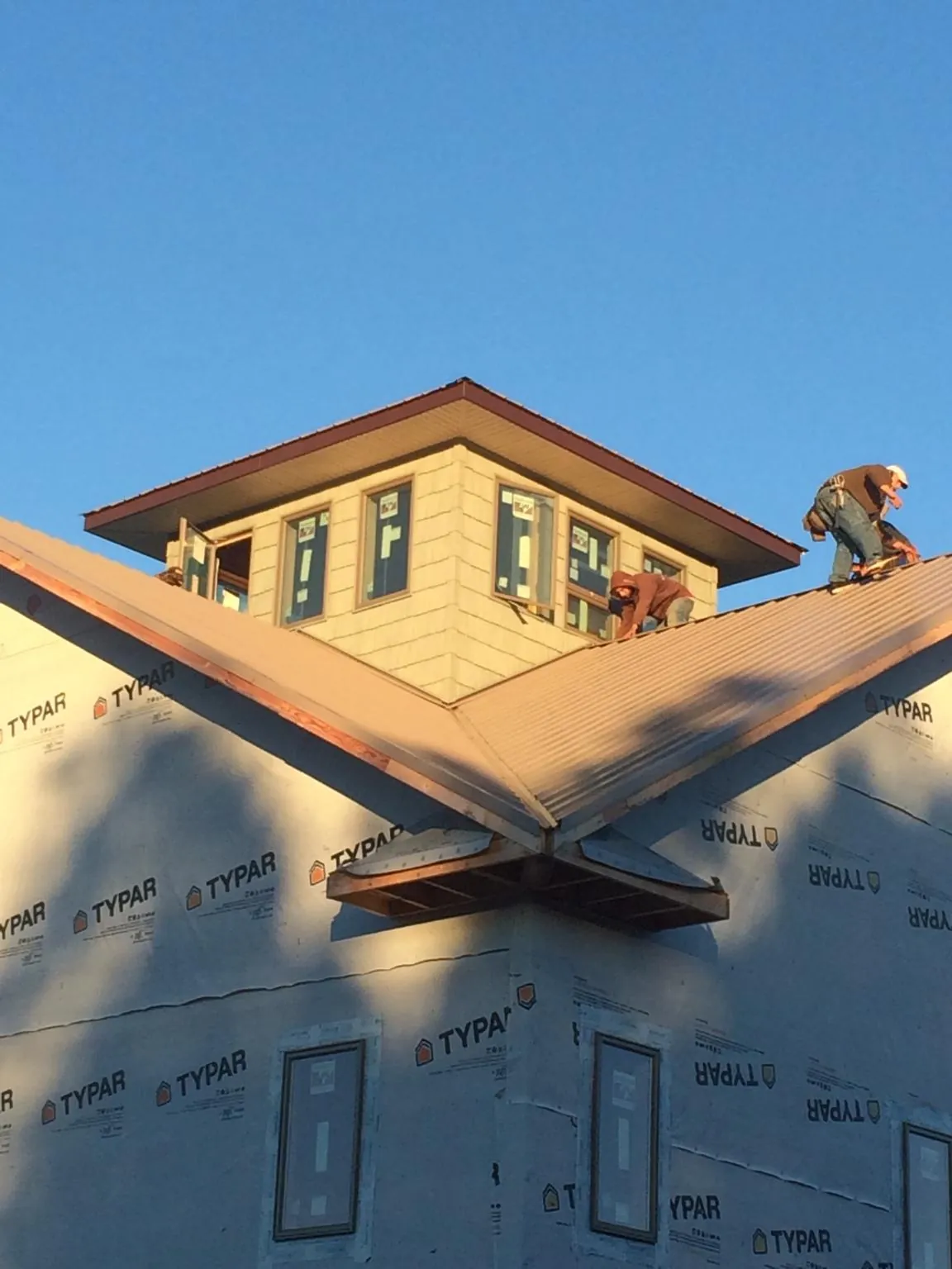 Roofers working around a rooftop cupola on a new metal roof at sunset — Roof Waterproofing in Poole by Roofing Brothers